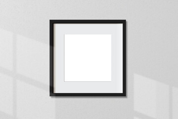 Minimal empty square black frame picture mock up hanging on white wall background with window light and shadow. isolate image