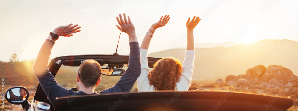 A loving couple enjoying the sunset and having fun in a convertible - obrazy, fototapety, plakaty 