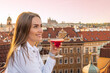 young woman with a cocktail on the roof in the center of Prague overlooking the Old Town Square