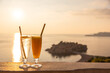 glass of juice on the background of the island of Sveti Stefan at sunset in Montenegro