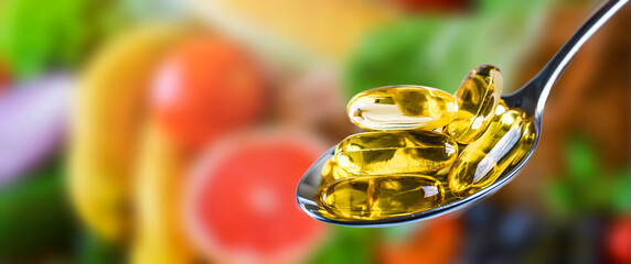 Capsules of Omega 3 oil on natural vegetable background.