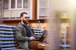 © F8  \ Suport Ukraine - Young handsome smiling man model sitting on the park bench using laptop outdoors