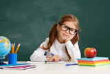 Fototapeta Panele - funny child   schoolgirl  girl student sitting at table near school blackboard