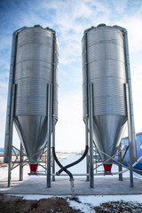 huge metal tanks for storing grain from the fields. Agricultural silos on a winter day