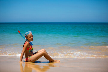 Happy child girl in a mask on the beach in summer