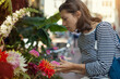 © papa - An attractive young woman picks flowers in an outdoor flower shop.
