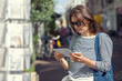 © papa - An attractive young woman chooses postcards in an outdoor gift shop.
