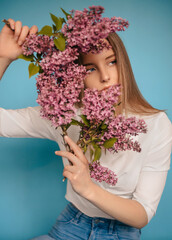 Woman hiding head in bouquet lilac flowers over colorful blue background