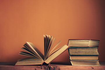 Poster - Old books on a old wooden table. Beautiful orange wall background.