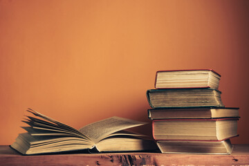 Poster - Old books on a old wooden table. Beautiful orange wall background.