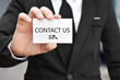 © banphote - Businessman hand holding business card with the message contact us. Idea for customer support hotline people connect