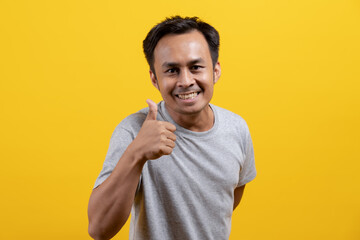 cheerful asian guy smile showing thumbs up hand and like symbol