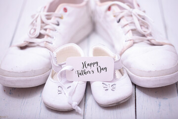 Two pairs of sports shoes on a white wooden background. The shoes of father and son or daughter. Fathers day concept.