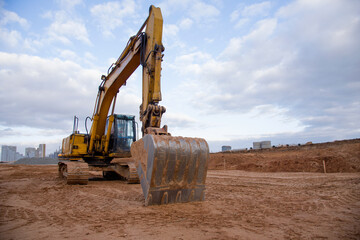 Excavator working at construction site on earthworks. Backhoe digs ground for the foundation and for paving out sewer line. Construction machinery for excavating, loading, lifting and hauling of cargo