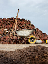 Wheelbarrow In Front Of A File Of Red Bricks With Shovels En Pipes