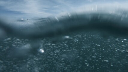 Wall Mural - Wave on moving water surface close up in the middle of the screen.  Under Water Surface in the middle of the sea