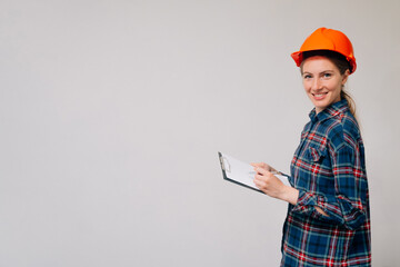 Female architect. Girl in a construction helmet looking at camera. A woman in a building uniform is smiling.