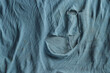 Grunge cloth for background. Texture of an old dirty ragged t shirt. Blue gray fabric with brown spots and holes. Crumpled torn rag
