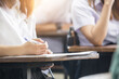 © panitan - high school,university student study.hands holding pencil writing paper answer sheet.sitting lecture chair taking final exam attending in examination classroom.concept scholarship for education abroad