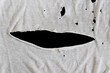 © ed2806 - Grunge damaged cloth on black background. Gray white fabric with big hole. Texture of an old dirty ragged t shirt. Copy space