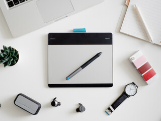 Poster - top view of office desk workspace with notebook, graphic tablet, smartphone and gadget on white background with copy space, graphic designer, Creative Designer concept.