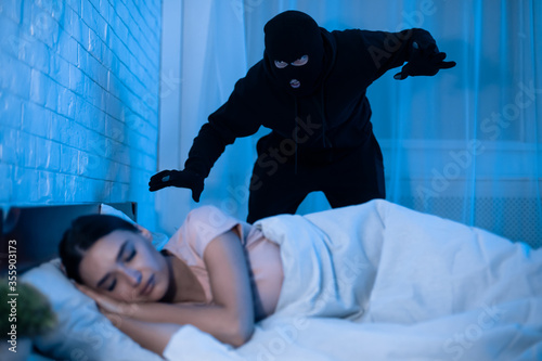 Cuadros en Lienzo Thief ready to attack woman who is sleeping in bed