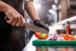 © pressmaster - Close-up of unrecognizable chef in apron cutting bell pepper with kitchen knife while making refreshing summer salad