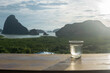 water glass on wood table in the morning sunrise of Samet Nang She is the best and famous view point on Phang nga bay in Southern Thailand.