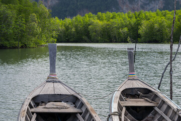 Two long tail boats moored at small pier near the mangrove forest in Thailand.