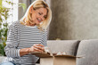 © InsideCreativeHouse - Happy middle aged woman customer taking out from box her shipment parcel at home