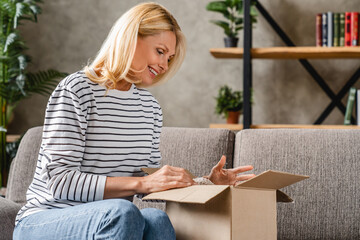 Smiling middle aged woman customer receive post shipment parcel at home