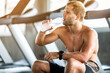 strong sportsman drinking cold fresh water and relaxing at sport gym, A break from intense exercise in the gym