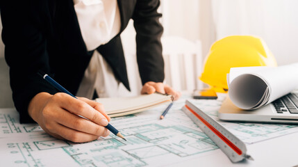 Two colleagues discussing data working and tablet, laptop with architectural project at construction site at desk in office