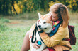 © Daniil - Girl plays with husky white ginger dog in park in fresh air. Feeling portrait of woman and cute foxy dog close-up. Beautiful red husky dog playing with girl in autumn colors. Walking pet with owner.