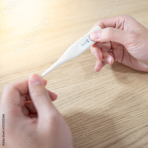 Measure Body Temperature Concept Male Hand Holding Digital Thermometer With 37 Celsius Degree Number On Monitor Display Check A Fever During Coronavirus Covid 19 Pandemic Stock Photo Adobe Stock