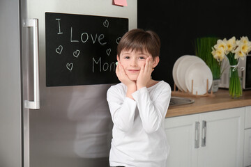 Canvas Print - Little boy near chalkboard on refrigerator in kitchen