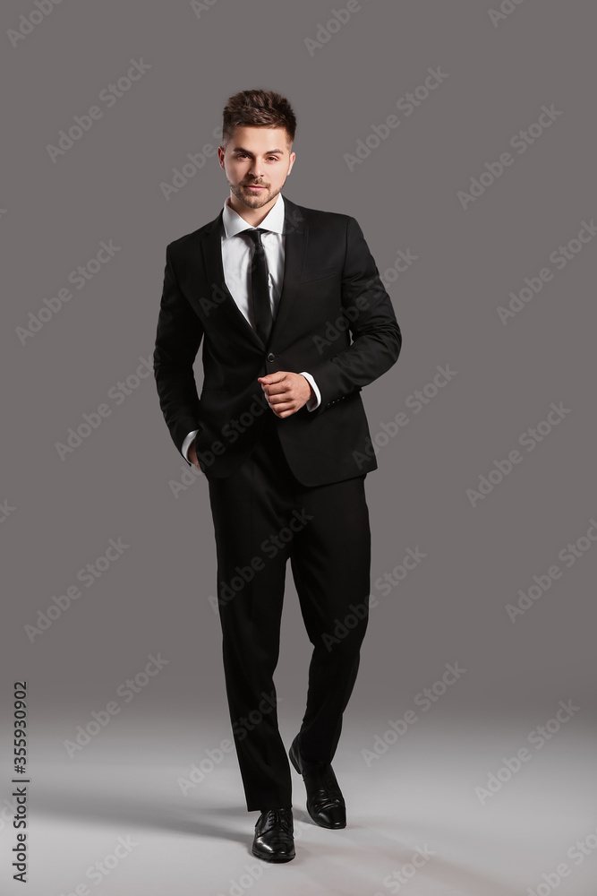 Handsome young man in elegant suit on grey background