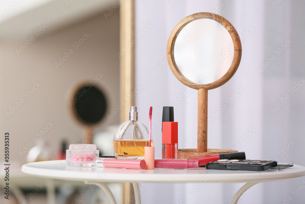 Different cosmetics and mirror on table in room