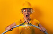 © alphaspirit - Worker girl with hat breaks an electric cable. Yellow background