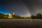 Fototapeta Tęcza - A rare event. Double rainbow in the blue sky over the city. Landscape on the river during the rain. Bridge and beautiful churches. Raindrops on the river. Green trees and grass. 