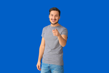 Sticker - Handsome young man pointing at viewer on color background