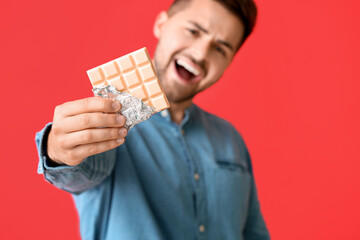 Sticker - Handsome young man with tasty chocolate on color background