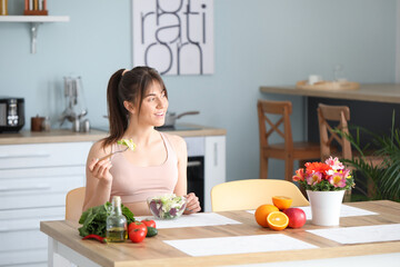 Sticker - Sporty young woman eating tasty salad in kitchen