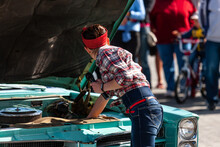 The Young Woman In Blue Jeans And .red And White Check Shirt Is Checking The Engine Of The Old-fashioned Car. Opened Hood Of Mentol Colored Rarity Car.