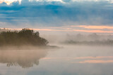 Fototapeta Niebo - Heavy fog on the river before the rain. Dense fog covers the river and forest in summer