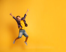 Happy And Emotional Child Jumps Over A Yellow Background.