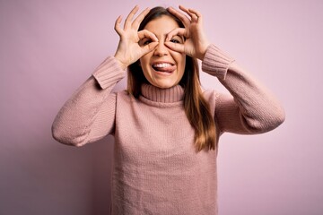 Sticker - Beautiful young woman wearing turtleneck sweater over pink isolated background doing ok gesture like binoculars sticking tongue out, eyes looking through fingers. Crazy expression.