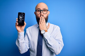 Sticker - Handsome bald business man with beard holding broken smartphone showing cracked screen cover mouth with hand shocked with shame for mistake, expression of fear, scared in silence, secret concept