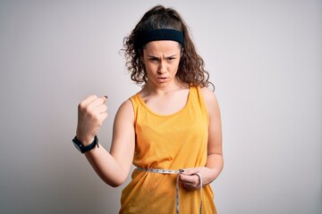 Poster - Young beautiful woman with curly hair controlling weight using tape mesure annoyed and frustrated shouting with anger, crazy and yelling with raised hand, anger concept