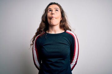 Poster - Young beautiful woman with curly hair wearing casual sweater over isolated white background making fish face with lips, crazy and comical gesture. Funny expression.